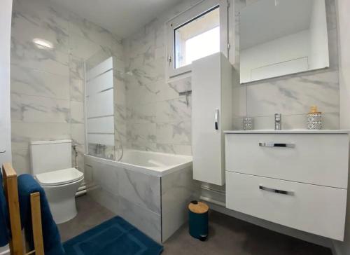 La salle de bains blanche est pourvue d'une baignoire et de toilettes. dans l'établissement Studio cosy entre Disney et Paris, à Torcy