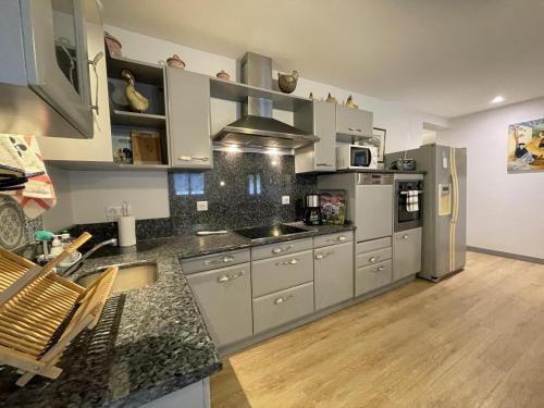 a kitchen with stainless steel appliances and wooden floors at Ene chocoa in Louhossoa