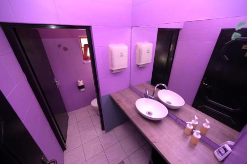 a purple bathroom with two sinks and a mirror at OFOO Zagreb in Zagreb
