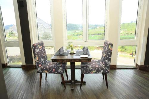 a table and two chairs in a room with windows at Pedro Barn Hotel at Little England Cottages in Nuwara Eliya