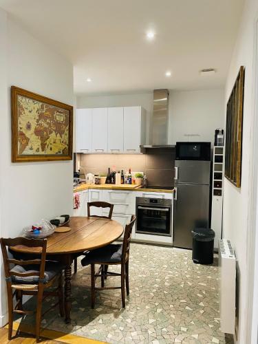 une cuisine avec une table en bois et une table et des chaises dans l'établissement Charmant 2 pièces aux portes de Paris, à Levallois-Perret