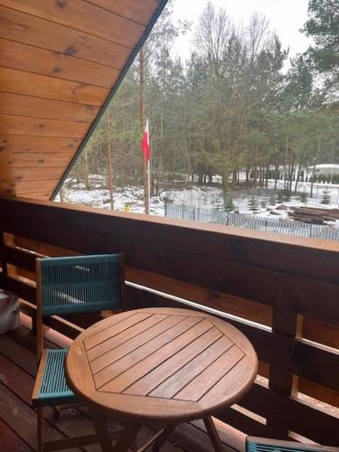 a table and two chairs on a porch with a window at Domek Zielona Sowa in Siemianówka