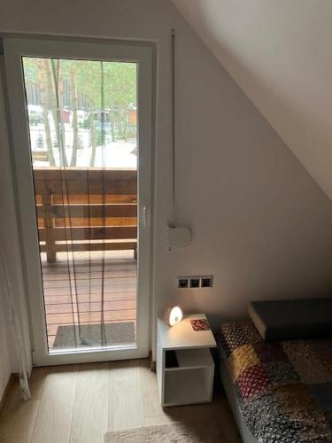 a bedroom with a bed and a sliding glass door at Domek Zielona Sowa in Siemianówka