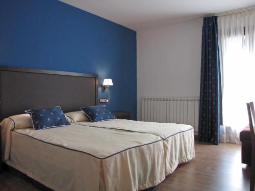 a bedroom with a large bed with blue walls at Hotel Sesué in Sesué