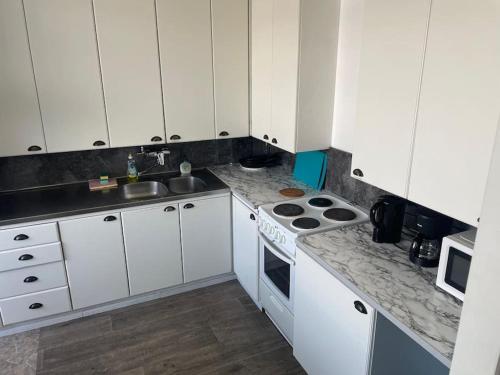 Una cocina con gabinetes blancos y un horno de estufa. en Asunto työporukalle Ollintie 1b2, en Uimaharju