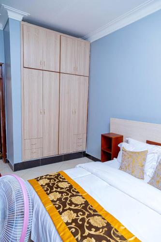 a bedroom with a large bed with wooden cabinets at Asante Apartments in Bulambiro