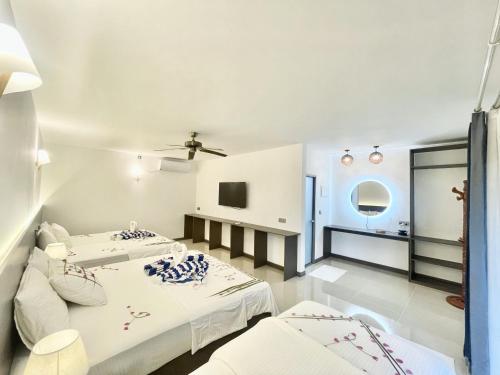 a bedroom with two beds and a tv at La Palma Suites in Ukulhas