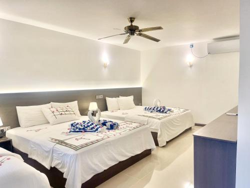 a bedroom with two beds and a ceiling fan at La Palma Suites in Ukulhas