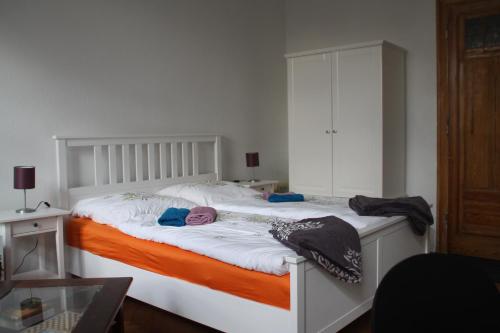 ein Schlafzimmer mit einem weißen Bett mit einer orangefarbenen Decke in der Unterkunft Apartment Altstadt Villa in Quedlinburg