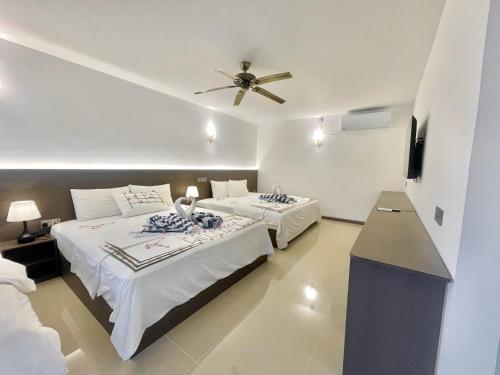 a bedroom with two beds and a ceiling fan at La Palma Suites in Ukulhas