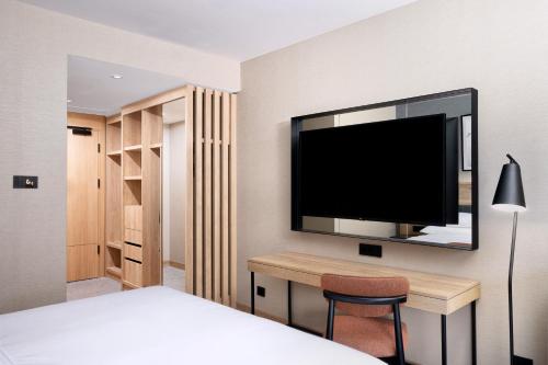 a bedroom with a bed and a desk with a flat screen tv at Four Points by Sheraton Bansko in Bansko
