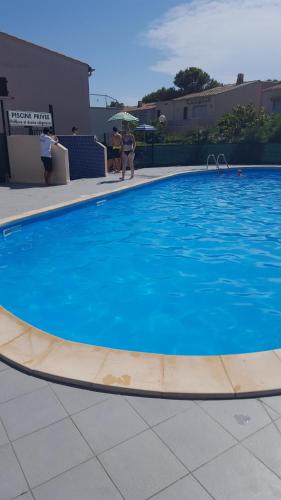 une grande piscine bleue avec des personnes debout autour de celle-ci dans l'établissement residence eureka T2 proche du camp, au Cap d'Agde