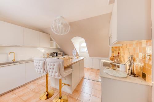 - une cuisine avec des placards blancs et une chaise dans l'établissement Escapade Luxe à Deux Pas des Champs-Élysées, à Paris