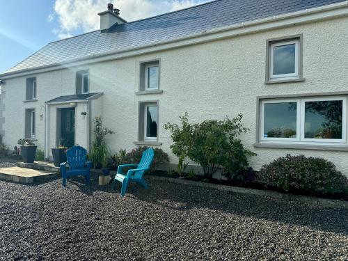 two blue chairs in front of a white house at Sweet Lamb Farmhouse in New Ross