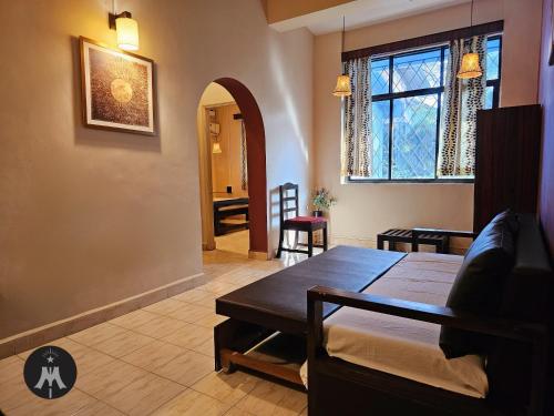 a living room with a bed and a dining room at Bijou Guest House in Baga