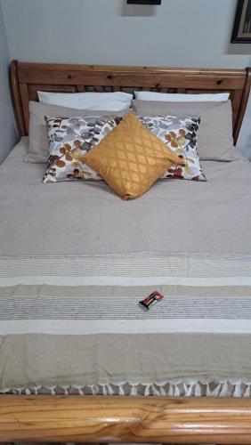 una cama con varias almohadas en At Home Guest House, en Postmasburg