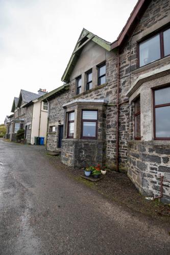 an old stone house with some plants on a street at Spindrift in Mallaig