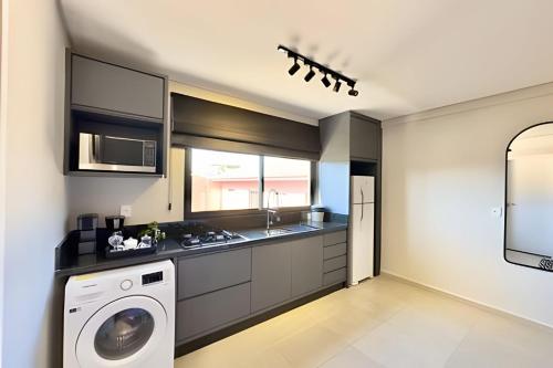 a kitchen with a washer and a washing machine at Studio com ar-condicionado no Centro! in Guarapuava