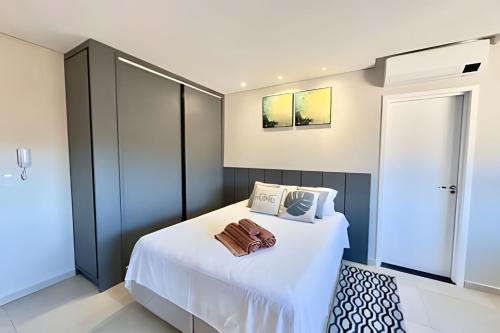 a bedroom with a bed with white sheets and pillows at Studio com ar-condicionado no Centro! in Guarapuava