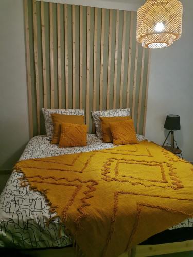 a bedroom with a bed with a yellow blanket and pillows at Appartement calme en rdc in Vila Verde