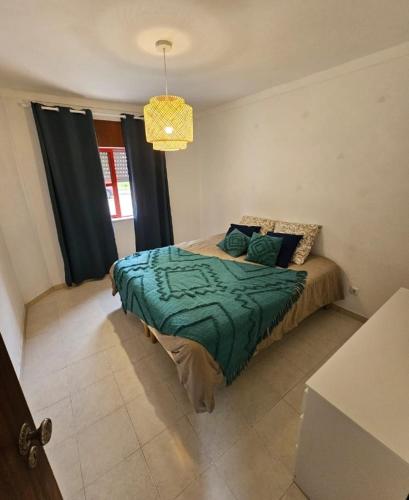 a bedroom with a bed with a green comforter at Appartement calme en rdc in Vila Verde