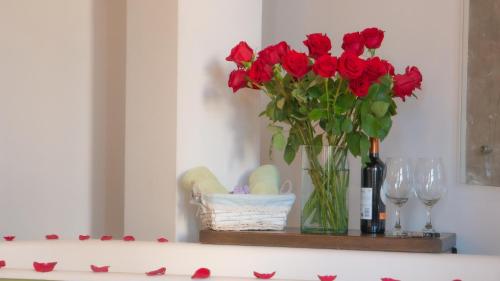 a vase of red flowers and wine glasses on a table at Boutique Hotel in Quito Hotel Casona 1914 in Quito