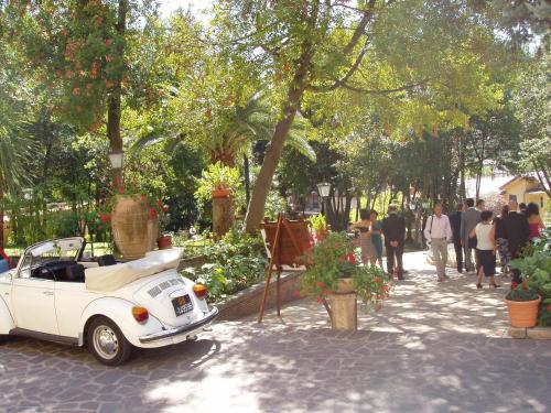 an old white car parked on a sidewalk next to trees at Hotel Il Cavalier D'Arpino in Arpino