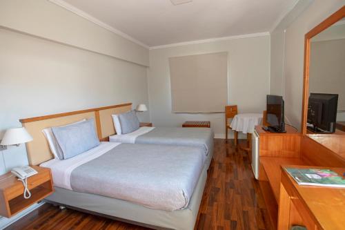 a hotel room with two beds and a television at Gran Hotel Vicente Costanera in Puerto Montt