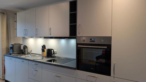 a kitchen with white cabinets and a stove top oven at Penzhaus - Premium Private Suites in Zell am Ziller