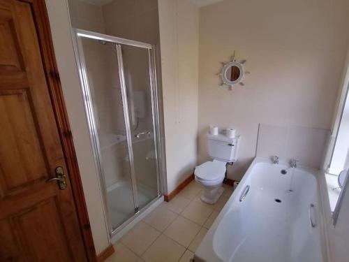 a white bathroom with a shower and a toilet at Rossole Cottage in Enniskillen