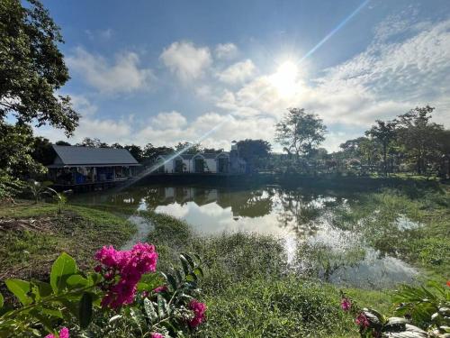 a view of a lake with a house and flowers at Cozy breezing countryside Pet in Ban Khlong Sip Sam Lang