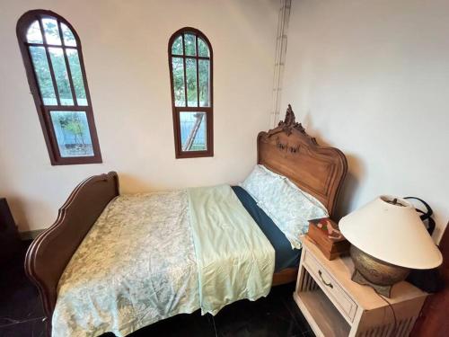 a bedroom with a bed and a lamp and two windows at Cozy breezing countryside Pet in Ban Khlong Sip Sam Lang