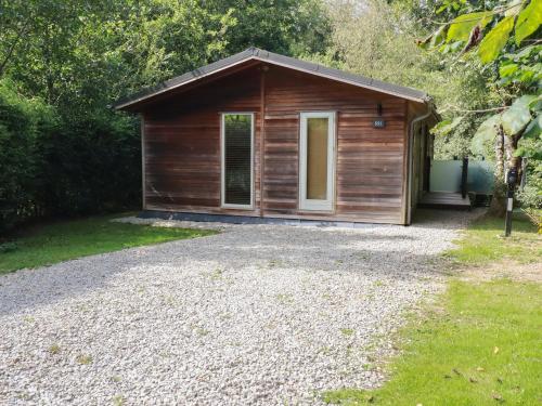 a small wooden cabin with a gravel driveway at 1 Streamside in Looe