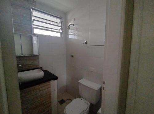 a bathroom with a toilet and a sink and a window at Apartamento no Centro in Piracicaba