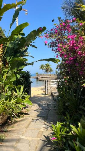 a path leading to a beach with pink flowers at GUEST HOUSE Floresta Mar in Angra dos Reis