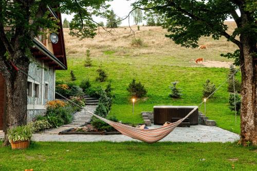 a hammock in a yard next to a house at Chałupa na wsi u Papierzy Sauna, Jacuzzi, SPA in Witów