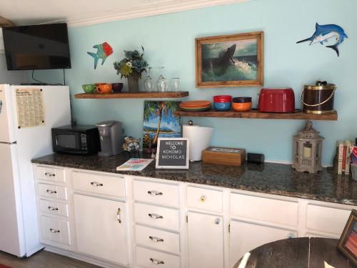 a kitchen with a counter with a microwave and a refrigerator at Romantic Beach Style Cottage close to everything! in Whitehouse Plantation