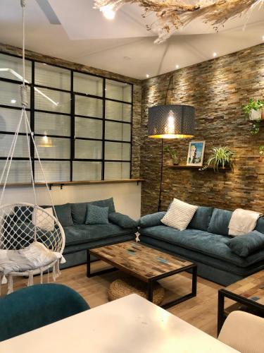 un salon avec des canapés bleus et une table dans l'établissement La Verrière Berges du Tarn - Centre historique, à Millau