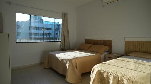 a bedroom with two beds and a window at Residencial Maria Idia in Bombinhas