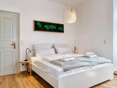 - un lit blanc dans une chambre blanche avec une lampe dans l'établissement SCHEE Apartments am Löpsinger Tor, à Nördlingen