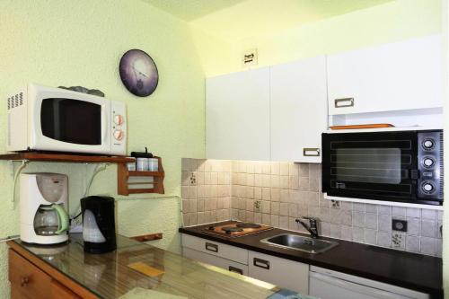une cuisine avec un micro-ondes et un évier dans l'établissement Résidence Le Cairn - Résidence Cairn - Studio 4 personnes vue pistes MAE-6351, aux Orres