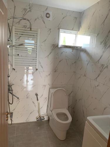 a white bathroom with a toilet and a window at Ranch Cozy Inn in Mtskheta