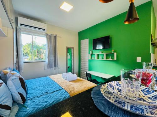 a green room with a bed and a table at Stúdio equipado em Xerém - St 6 in Xerém