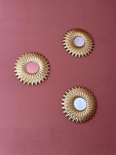three gold sunburst mirrors on a red wall at Savanah - Olympe Suites & Spa Roubaix - Lille in Roubaix