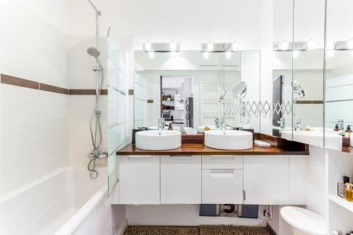 une salle de bain avec deux lavabos et un miroir dans l'établissement Calme dans la verdure Paris 16e, à Paris