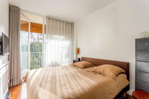 une chambre avec un lit et une grande fenêtre dans l'établissement Calme dans la verdure Paris 16e, à Paris