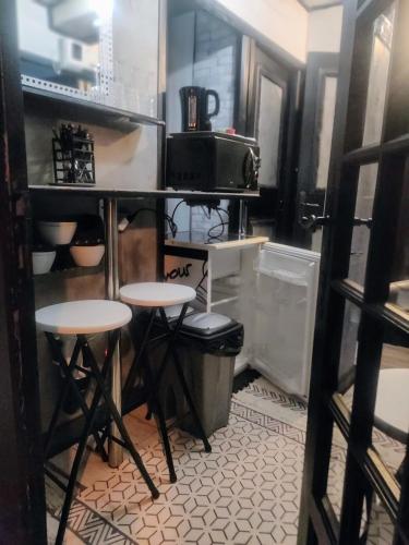 a kitchen with two stools and a table with a microwave at 2CH 4pers matelas M de Forme Kitchenette SDB WC au calme côté jardin in Tulle