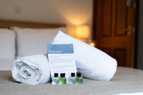 a pile of towels on a bed with two bottles at Woodlands House with Hot Tub in Ballachulish