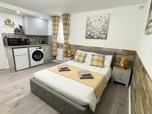 a bedroom with a large bed and a kitchen at Gatwick Lodge in Horley