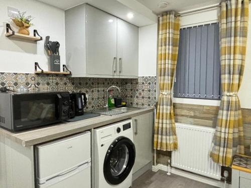a kitchen with a washing machine and a microwave at Gatwick Lodge in Horley